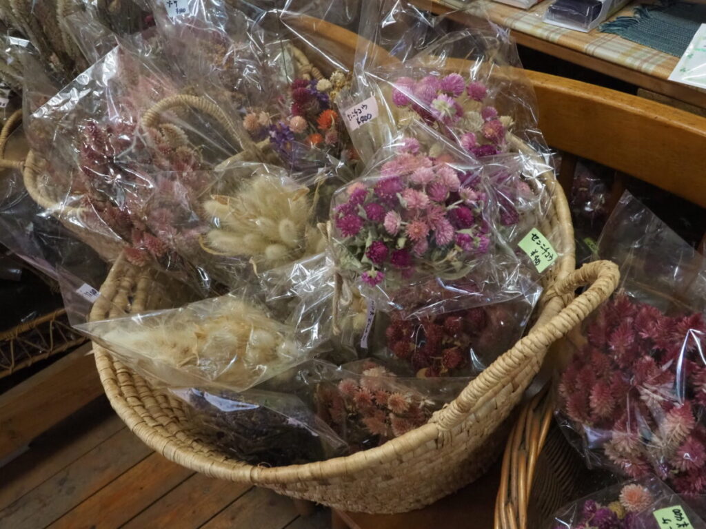 Woven baskets filled with dried flowers of various colors, displaying the vibrant and natural beauty of Ai no Sato’s herb garden harvest.